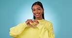 Heart, hands and face of woman in studio for kindness, care and charity donation on blue background. Happy portrait, indian model and review of love, hope and thanks for support, emoji sign and peace