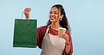 Waitress woman, coffee and studio with smile, bag and face for service, food and gift by blue background. Barista girl, small business and present with matcha, tea and happy for catering at cafe job