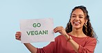 Woman, go vegan sign or poster in studio, face or happy for choice, opinion or diet by blue background. Girl, paper billboard or banner in protest, nutrition or accountability with voice for decision