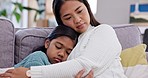 Comfort, love and mother hugging her child on a sofa in the living room of family house. Sad, depression and Asian mom embracing her girl kid with care, support and compassion in the lounge at home.