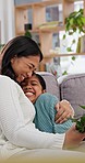 Child giving mom flowers, hug and gift for mothers day with love and happiness at family home. Bouquet, present and woman kiss young girl on forehead, birthday and celebration with smile on couch