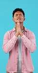 Man, praying or begging, worship and hope to win competition, faith and God on blue background. Spiritual, guidance and religion with prayer in studio, trust and opportunity with plea and question