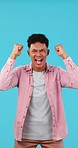 Man, excited about winning and cheers in studio, happiness and celebration with fist isolated on blue background. Competition, giveaway or lotto with success, announcement and good news for winner