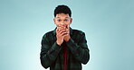 Face, wow and alarm with the reaction of a man in studio on a blue background looking shocked at news. Portrait, surprise and mind blown with a young person hearing a secret, announcement or gossip