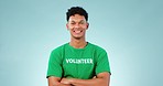 Volunteer man, arms crossed and studio with smile, face or promo for earth day by blue background. Ecology activism, person and leader for global warming, climate change or happy for safety of planet