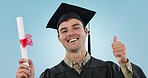 Graduation, man and thumbs up in studio, smile and face for achievement, goal or diploma by blue background. College student guy, certificate and emoji in portrait for education, review and success