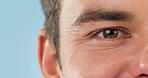 Closeup, vision and eye of a man on a blue background for optometry, wellness and a health check. Zoom, eyes and a person with eye care, ophthalmology medicine or contact lenses to see on a backdrop