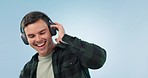 Music, headphones and happy man dance in studio with freedom, energy and celebration on blue background. Moving, face and male model with radio earphones or streaming subscription to audio podcast