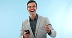 Celebration, phone and face of businessman in a studio with fist pump for success or achievement. Happy, excited and portrait of male winner with online bet victory with cellphone by blue background.