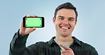 Green screen, phone and face of man with hand pointing agreement in studio with mockup on blue background. Smartphone, display and portrait of male model show app, support or sign up emoji promotion