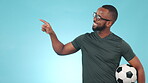 Black man, sports and studio with pointing for football with list for fitness as coach, advice or happy. Soccer person, exercise and trainer for athlete or portrait for motivation or blue background