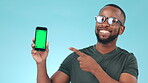 Phone, green screen and pointing to a screen with a black man in studio on a blue background. Website, perfect and chromakey on a mobile display with tracking markers for marketing or advertising