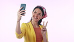 Selfie, profile picture and peace sign with a woman influencer in studio on a blue background for a status update. Phone, smile and photo with a happy young content creator posing for social media