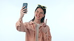 Selfie, social media and peace sign with a woman influencer in studio on a blue background for a profile picture. Phone, smile and photo with a happy young content creator posing for a status update