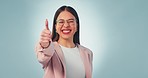 Happy, face and woman with thumbs up in studio with motivation, excited or thank you sign on blue background. Smile, portrait and female model show hand, success or emoji for well done and support