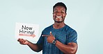 Happy black man, fitness and hiring sign for job opportunity or offer against a studio background. Portrait of African active male person or gym owner smile showing billboard or poster for recruiting