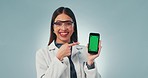 Science woman, phone and green screen in studio with point, face and review for medical app by blue background. Doctor, smartphone and mockup space with tracking markers for feedback with promotion