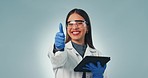 Scientist woman, tablet and thumbs up in studio for review, agreement or choice with face by blue background. Happy research expert, digital touchscreen and sign language for choice, vote or feedback