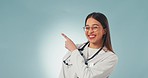 Woman, doctor pointing at advertising presentation and health information with news on blue background. Portrait, mockup space and medical services with marketing or healthcare promotion in studio