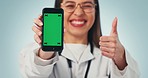 Doctor, woman showing phone and green screen in studio for telehealth, online healthcare and expert advice. Medical professional, chromakey and girl with digital app for health on blue background.