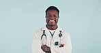 Face, happy black man and doctor with arms crossed for healthcare, wellness and career. Portrait, smile and confident medical surgeon in studio isolated on a blue background mockup space in Nigeria