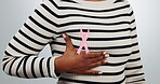breast cancer, pink and ribbon on chest of person in studio for medical, awareness and support. Healthcare, community and sign with closeup of bow on white background for solidarity and campaign