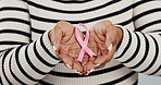 Breast cancer, medical and ribbon with hands of person in studio for pink sign, awareness and support. Healthcare, community and sign with closeup of bow on white background for solidarity campaign