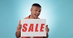 Billboard, discount and face of happy man in studio with yes sale, deal or announcement on blue background. Poster, promo code and portrait of guy model with retail, banner or news, offer or cashback