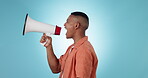 Megaphone, politics and a man speaker shouting on a blue background in studio for motivation at a protest. Change, speech or announcement with a young person at a rally screaming into a bullhorn