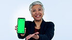 Face of businesswoman, presentation or green screen on a phone for social media advertising or online branding. Blue background, talk or mature lady pointing to show mobile app mockup space in studio