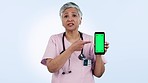 Green screen, phone and senior woman doctor with no, warning or review in studio on blue background. Smartphone, presentation and and portrait of old lady nurse show feedback, caution or safety tips