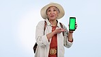 Green screen, face and senior woman with hand pointing in studio for travel, deal or discount on blue background. Smartphone, space and portrait elderly lady customer show online shopping sign up app