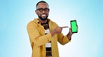 Happy black man, pointing and phone green screen in advertising or marketing against a studio background. Portrait of African male person smile showing mobile smartphone app, display or mockup space