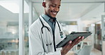 Tablet, medical and happy black man doctor on internet for research or healthcare information online in a hospital. Smile, medicine and professional typing on health website or app in a modern clinic