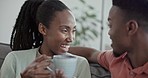 Happy couple relax on sofa with coffee, conversation and morning bonding together in home living room. Smile, black man and woman on couch with drink, marriage discussion and love in house in Africa.