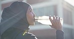 Moslem woman, drinking water and relax with water bottle by fitness, wellness and workout in city. Athlete, cardio and break from running with satisfaction, happy and active lifestyle by lens flare