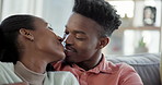 Love, kiss and happy black couple on sofa in home living room, bonding and romance. Intimate, African man and woman smile, talking on couch in lounge and healthy relationship, commitment and care