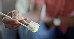 Restaurant, hand and eating sushi for lunch, closeup food and nutrition with seafood. Plate, hungry and chopsticks with a person for Asian cuisine, food or Japanese culture for dinner or fine dining