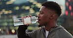 Breathing, fitness and drinking water with black man with workout, training and exercise outdoor to relax. Sport, urban rooftop and city with a male athlete with drink, hydration and rest from sports