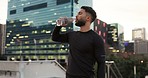 Wellness, fitness and drinking water with man with workout, training and exercise outdoor to relax. Sport, urban rooftop and city with a male athlete with drink, hydration and rest from sports