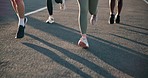 People, legs and running on road in exercise, outdoor fitness or cardio training on asphalt. Closeup of active or athlete group of runners feet in sprint, race or practice on street for lose weight