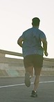 Black man, fitness and running on road for workout, outdoor exercise or cardio training in urban town. Rear view of active male person, athlete or runner in sports, healthy wellness or lose weight