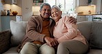 Senior couple, face and hug on sofa, smile and bonding with love, support and relax in retirement in home. Elderly woman, old man and happy with embrace, together and sitting on living room couch