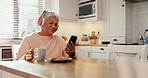 Headphones, cellphone and senior woman in the kitchen watching funny, comic or comedy video on social media. Happy, smile and elderly female person reading post online with phone, coffee and biscuits