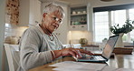 Senior woman, documents and laptop for bills, budget and financial planning or asset management in home kitchen. Elderly person on computer and writing on paper for policy, life insurance or mortgage