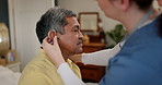 Old man, nurse help with hearing aid and elderly care, person with disability and woman with support. Health, wellness and caregiver with deaf patient, homecare and retirement with medicine and trust