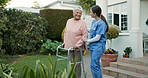 Walker, walking and caregiver help senior woman at a retirement home as support and care in a backyard. Movement, recovery and nurse with elderly person for rehabilitation at outdoor house for health