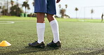 Soccer, shoes and sports training at field to workout for healthy body exercise, fitness and wellness. Football, closeup and legs of kid on grass, jump and practice for game, competition and match