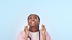 Doctor, woman and cross fingers in studio for wish, prayer and luck with stress at job by blue background. Medic, nurse and praying for sign, emoji or icon for results, change and healthcare report