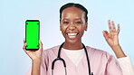 Doctor, smile and phone with green screen, ok and pointing to mobile device for advertising. Happy black woman, marketing a medical promotion for commercial, hospital app and promotion in wellness